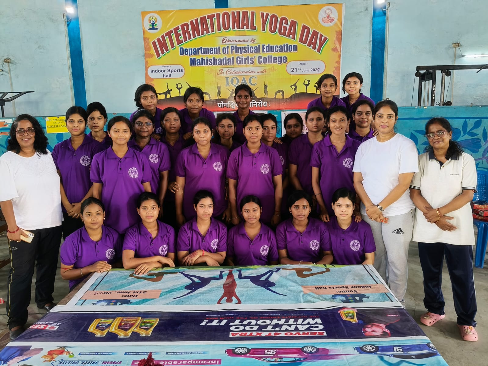 Group of students in purple T-shirts with International Yoga Day banner