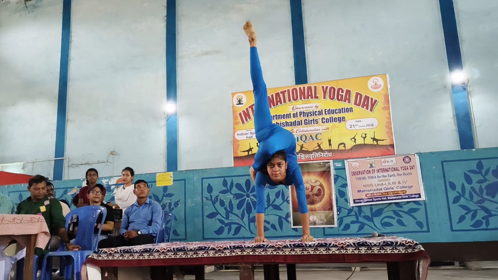 Student demonstrating a scorpion yoga pose on stage